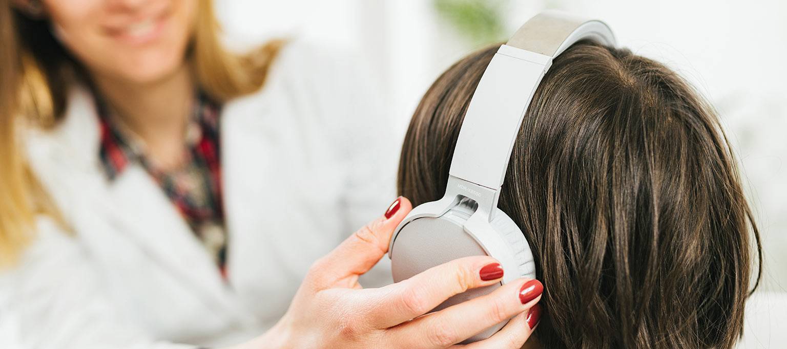 audiologist placing earphones on childs head
