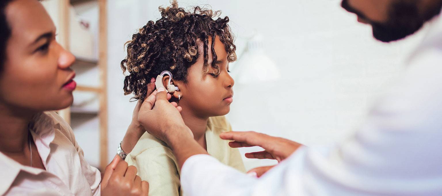 boy with mother and doctor testing hearing aid