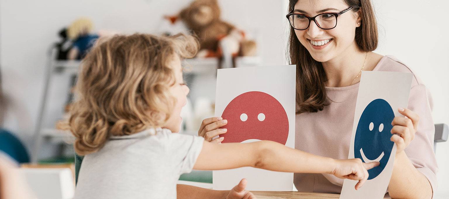 specialist woman helping young child communicate with cards