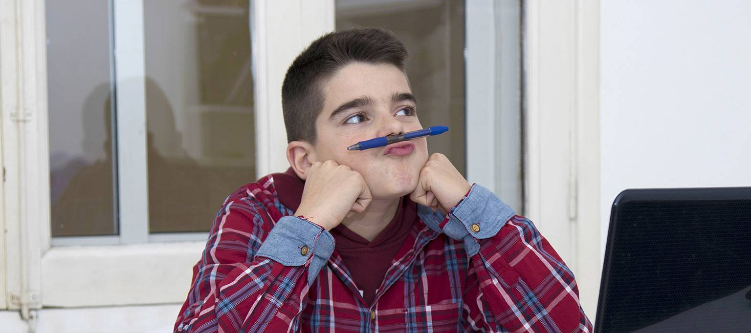 teen boy holding pen with top lip not paying attention