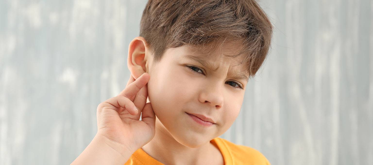 young boy holding fingers behind ears hard of hearing