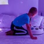 young boy in sensory colour room playing with toy