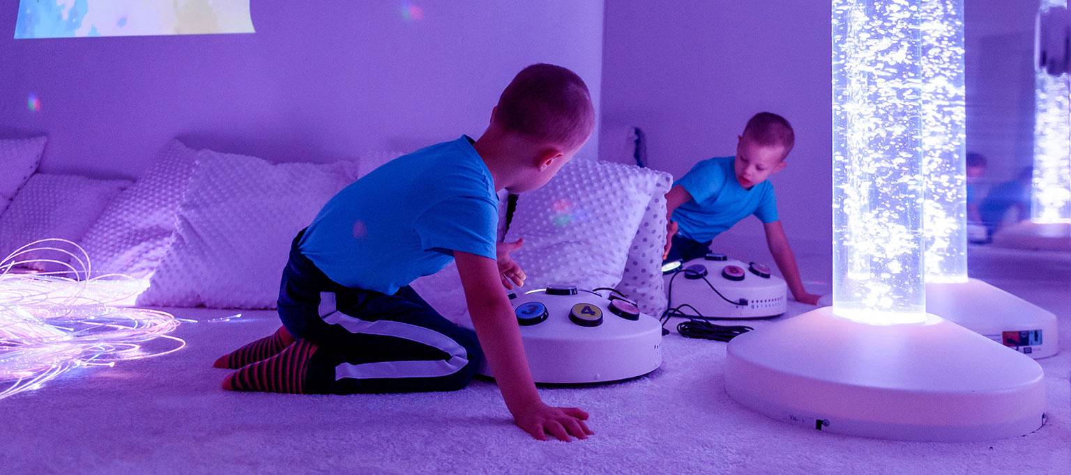 young boys in sensory colour room playing with toy