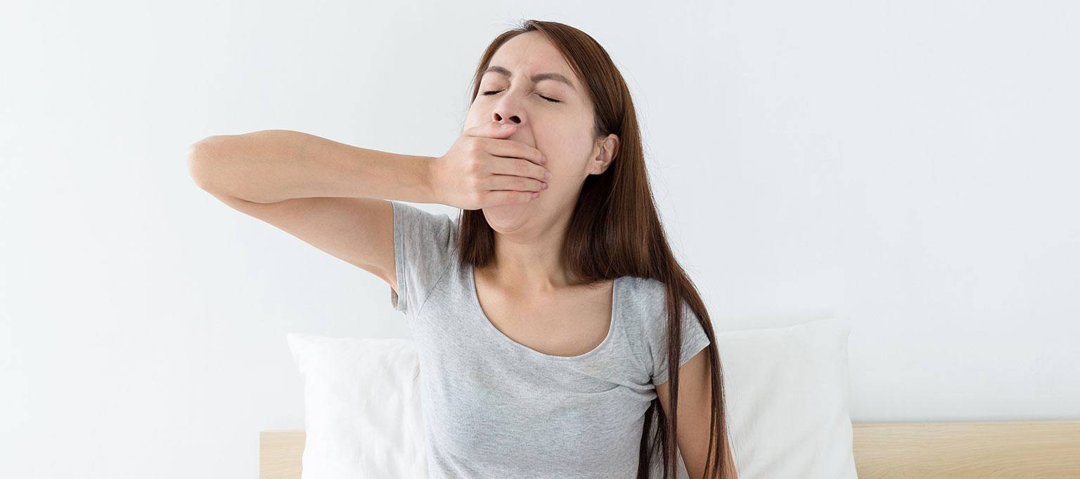 teenage girl yawning with hand over her mouth